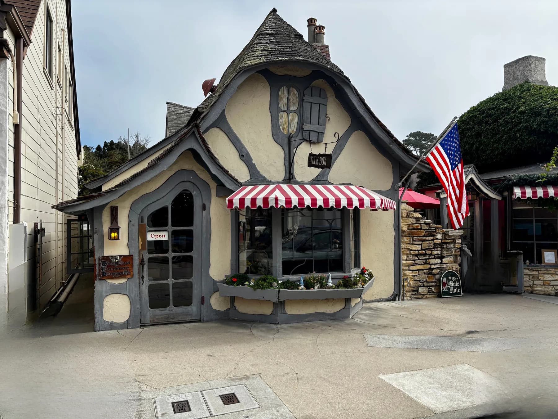 The Tuck Box, a storybook cottage with a steep curved roof and red-and-white awning